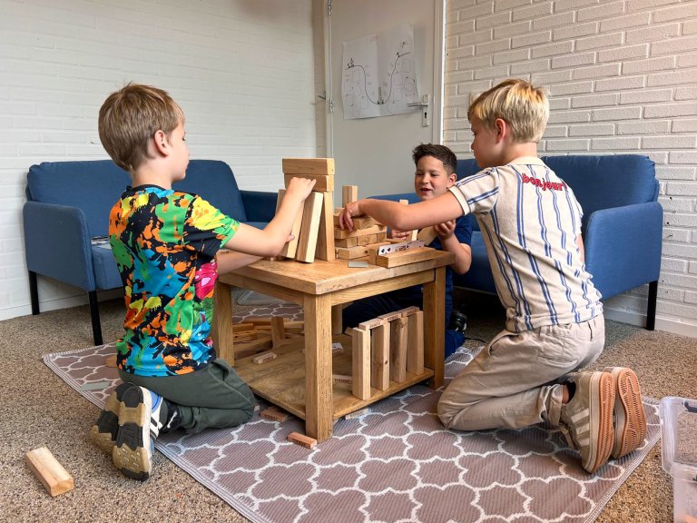 Drie kinderen zitten aan een tafel te spelen
